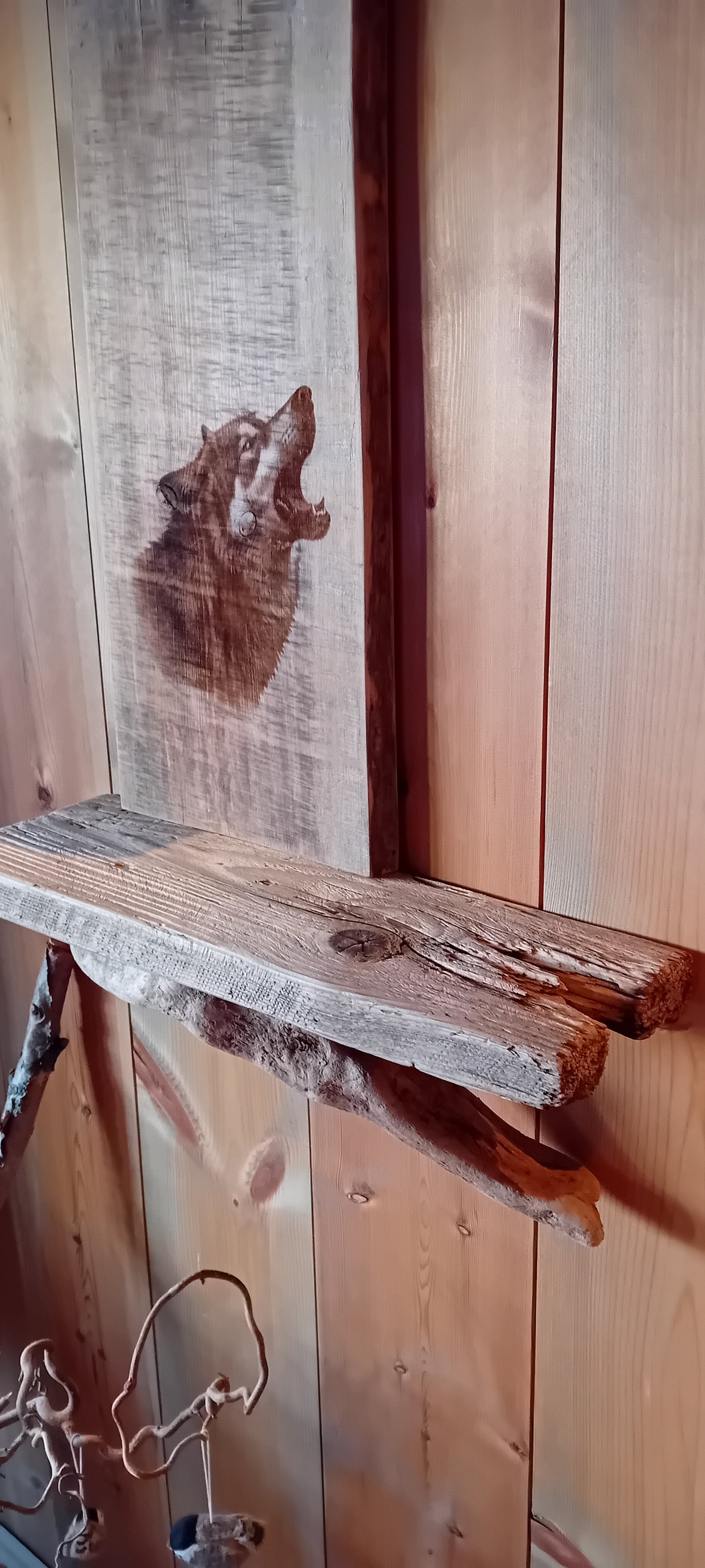 Vegghylle av grånet villmarkspanel og drivved med Ulvemotiv