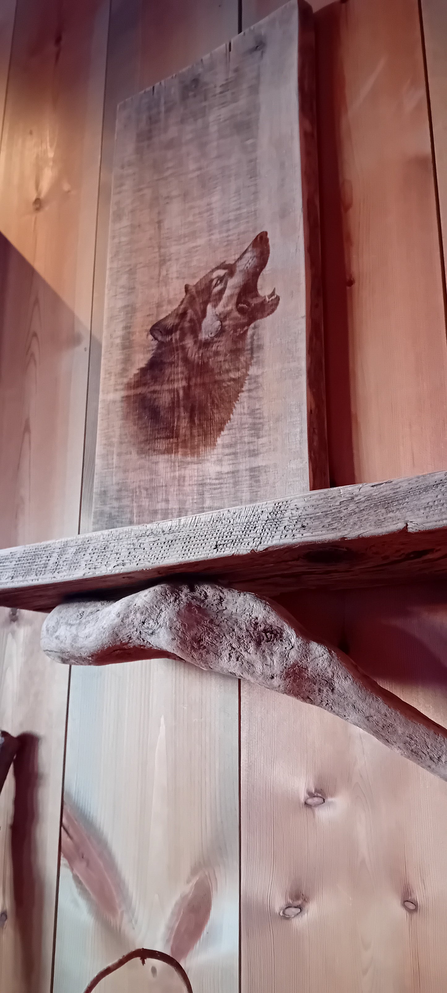 Vegghylle av grånet villmarkspanel og drivved med Ulvemotiv