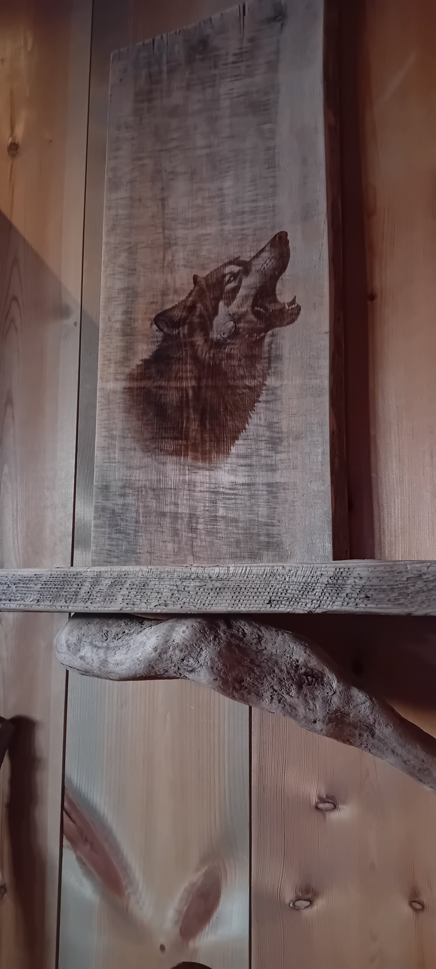 Vegghylle av grånet villmarkspanel og drivved med Ulvemotiv